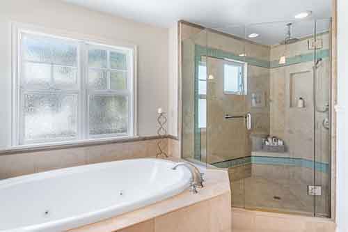 Primary bath with jacuzzi tub and spacious frameless shower at 3306 Highland